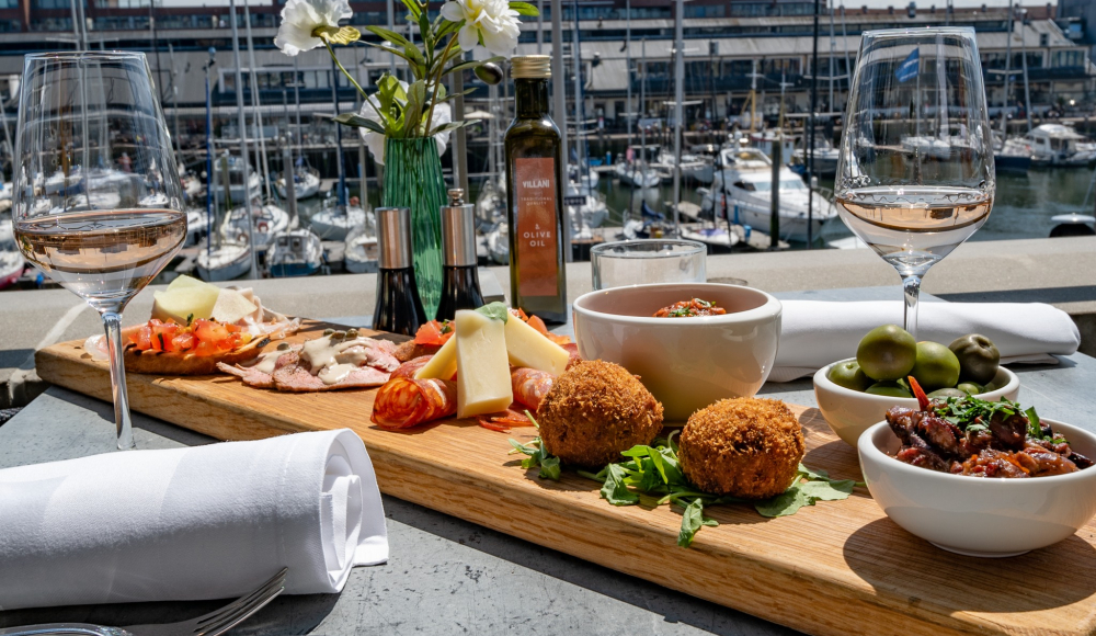 Een goed gevulde borrelplank bij restaurant Villani met de op de achtergrond de haven van Scheveningen Een goed gevulde borrelplank bij restaurant Villani met de op de achtergrond de haven van Scheveningen