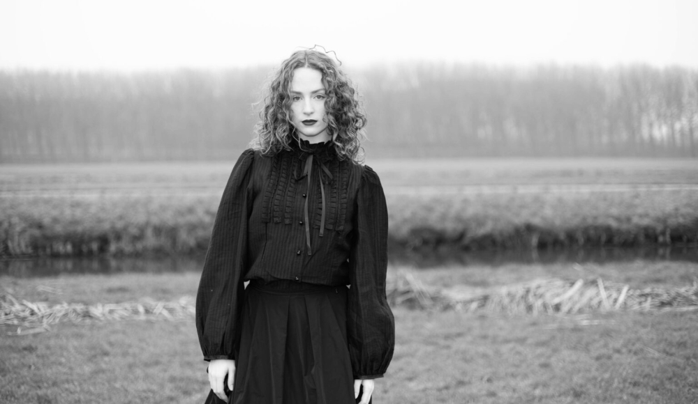 Zangeres Holly-Ann in een weiland in een sierlijke zwarte jurk in zwart-wit. Zangeres Holly-Ann in een weiland in een sierlijke zwarte jurk in zwart-wit.