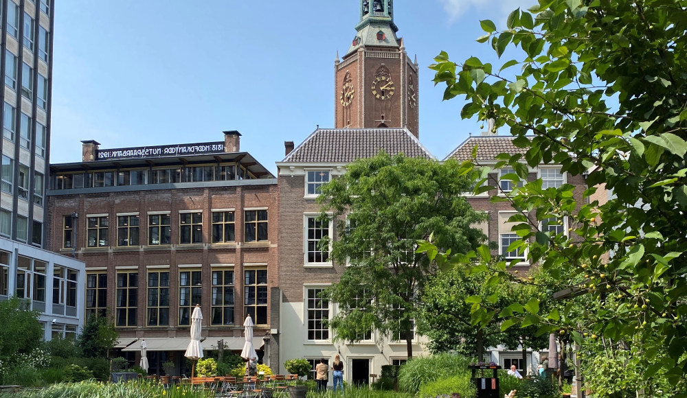 De Nutstuin achter het Nutshuis met op de achtergrond de Grote Kerk. De Nutstuin achter het Nutshuis met op de achtergrond de Grote Kerk.