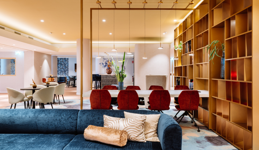 Moderne lounge van het Novotel World Forum met comfortabele zitplekken, vergadertafel en warme verlichting. Moderne lounge van het Novotel World Forum met comfortabele zitplekken, vergadertafel en warme verlichting.
