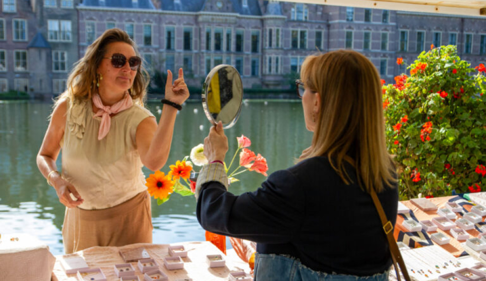 Bezoeker past sieraden bij kraam van de PrinsjesMarkt aan de Hofvijver