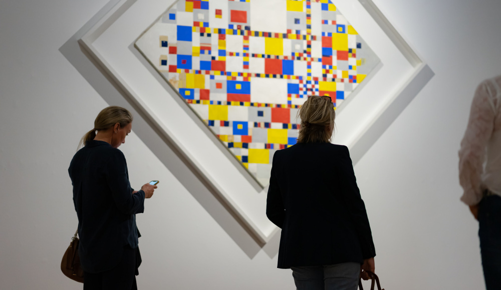 3 mensen bekijken een kunstwerk van Piet Mondriaan in het Kunstmuseum