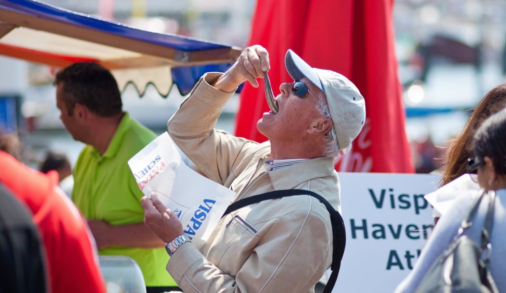 Een man hapt een nieuwe haring weg tijdens Vlaggetjesdag Scheveningen