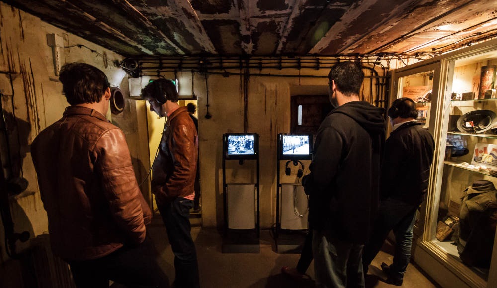 Mensen die kijken naar apparaten in het commandocentrum van het Atlantikwall Museum - Locatie Scheveningen Mensen die kijken naar apparaten in het commandocentrum van het Atlantikwall Museum - Locatie Scheveningen