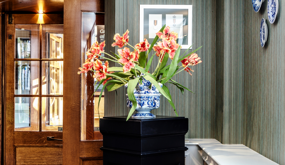 Elegant bloemstuk in een blauw-witte vaas op een zwarte sokkel in lobby Elegant bloemstuk in een blauw-witte vaas op een zwarte sokkel in lobby