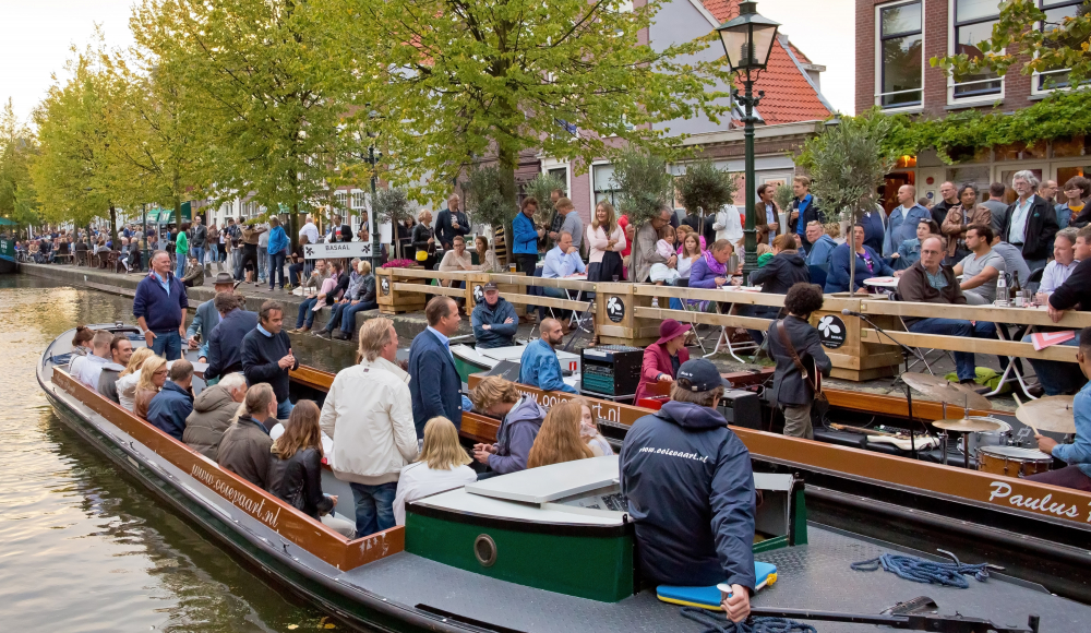 Mensen op boten en terras genieten van muziek langs de gracht Mensen op boten en terras genieten van muziek langs de gracht