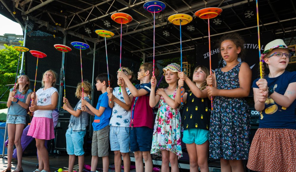 Kinderen krijgen circusles met jongleren van borden op podium Zeeheldenfestival