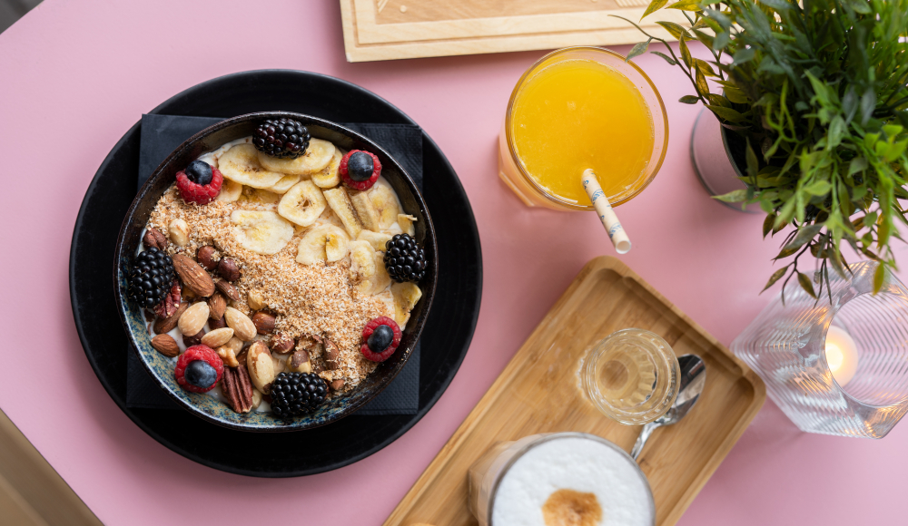 Topshot van een ontbijt met havermout met fruit, een glas jus d'orange en een cappucino. 