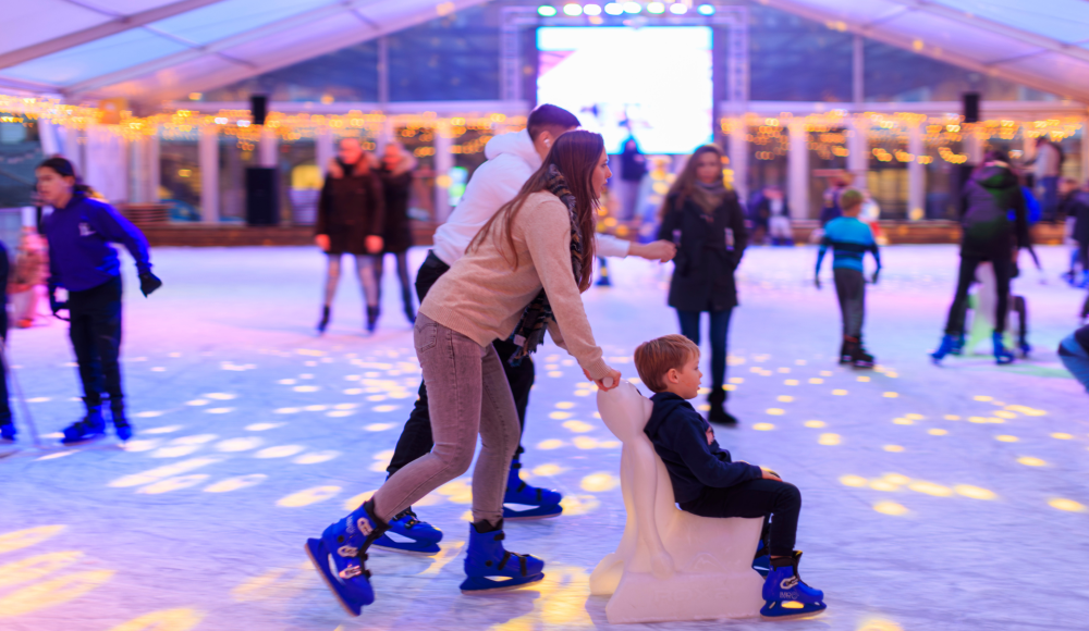 Child being pushed on the ice by an adult.