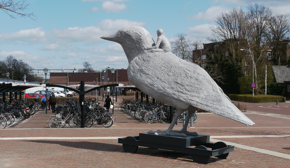 Een groot, wit sculptuur van een vogel met een persoon erop.