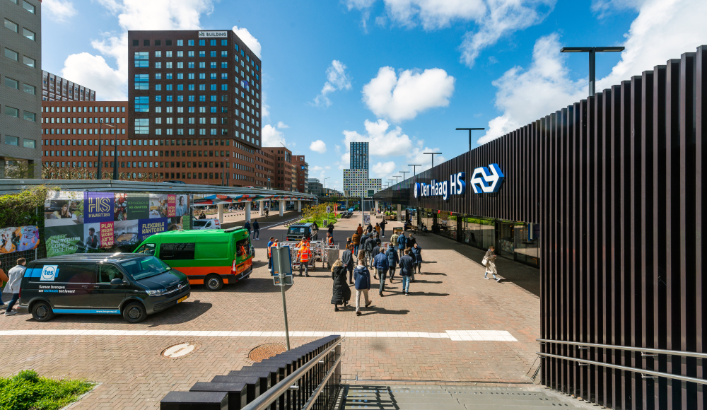 Drukke straat bij Station Den Haag HS met mensen en voertuigen. (c) Hugo de Wolf