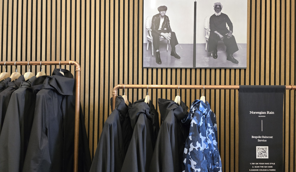 Raincoats hanging on a rack, with photos on the wall.