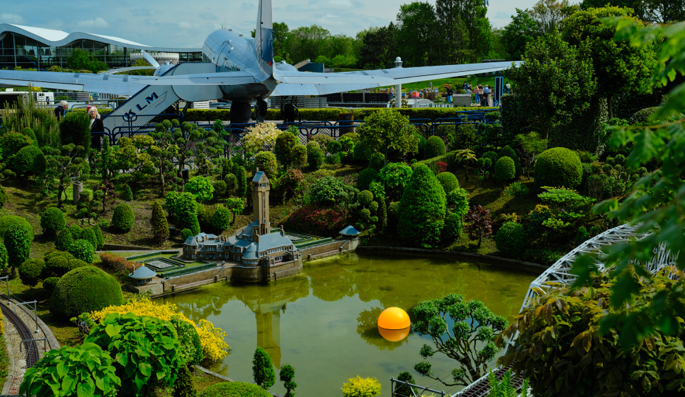 Een miniatuurpark met verschillende planten en een modelvliegtuig.