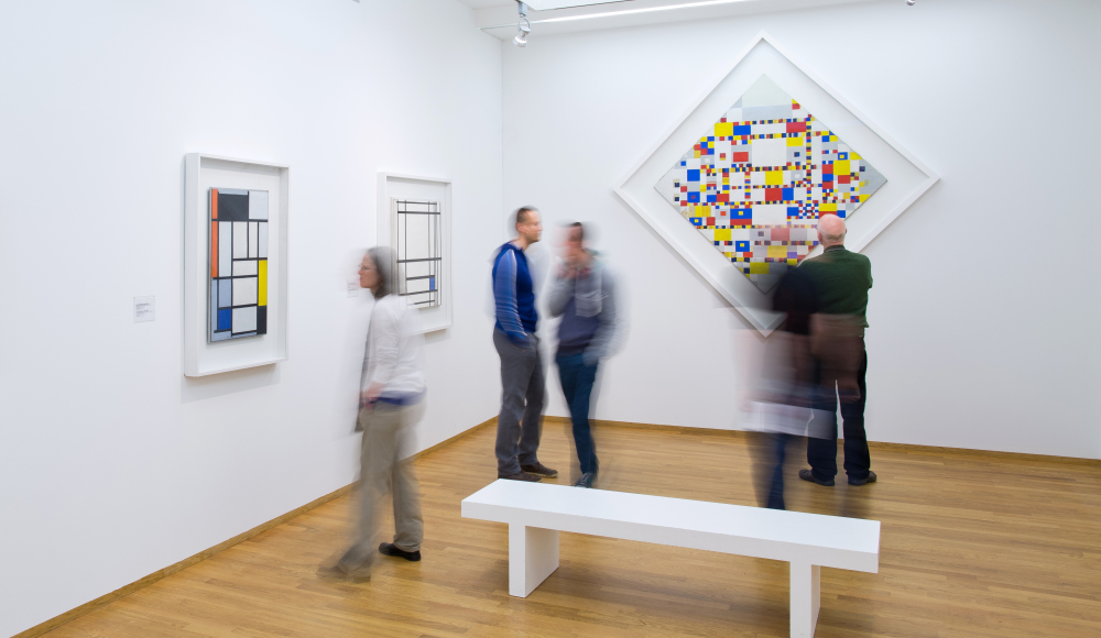 Mensen kijken naar de Victory Boogie Woogie van Mondriaan in Kunstmuseum Den Haag Mensen kijken naar de Victory Boogie Woogie van Mondriaan in Kunstmuseum Den Haag
