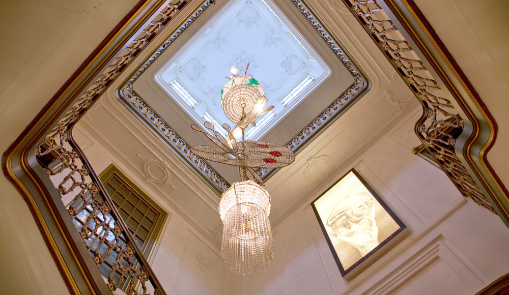 Doorkijk in het trappengat van museum Escher in het Paleis met een kroonluchter van Hans van Bentem Doorkijk in het trappengat van museum Escher in het Paleis met een kroonluchter van Hans van Bentem