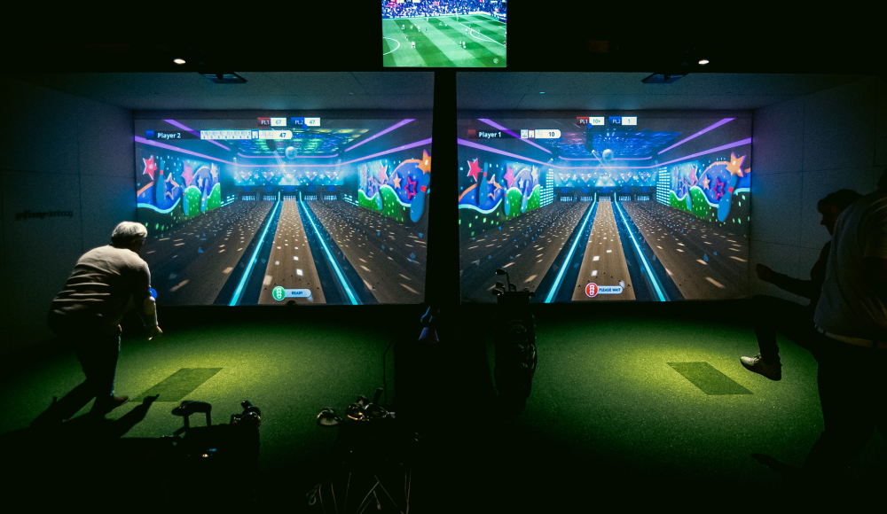 Two players engage in a bowling game on a large screen.