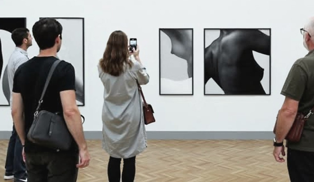 Vijftal mensen kijkt naar zwart-witte kunstwerken in een galerie.