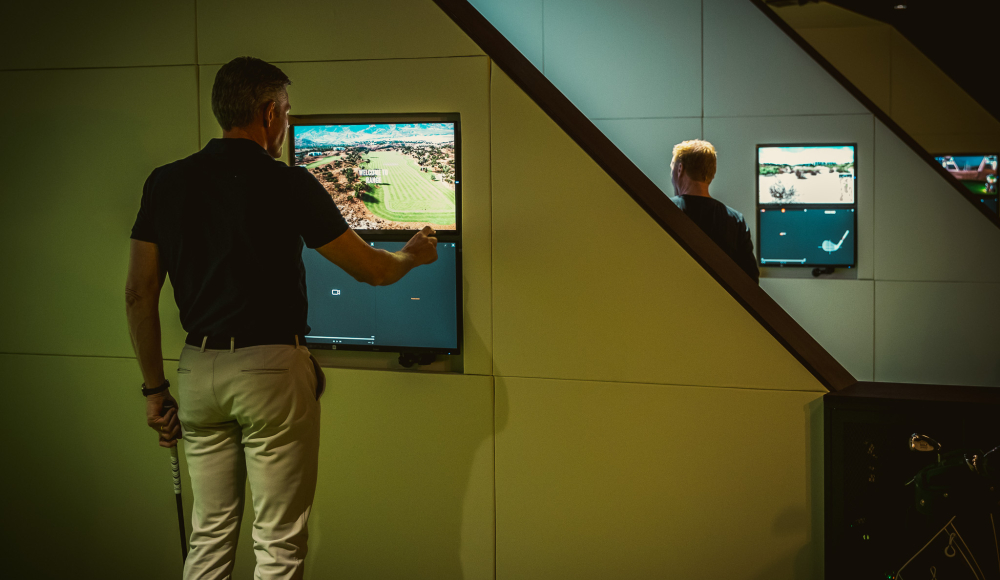 A man using a golf simulator with screens.