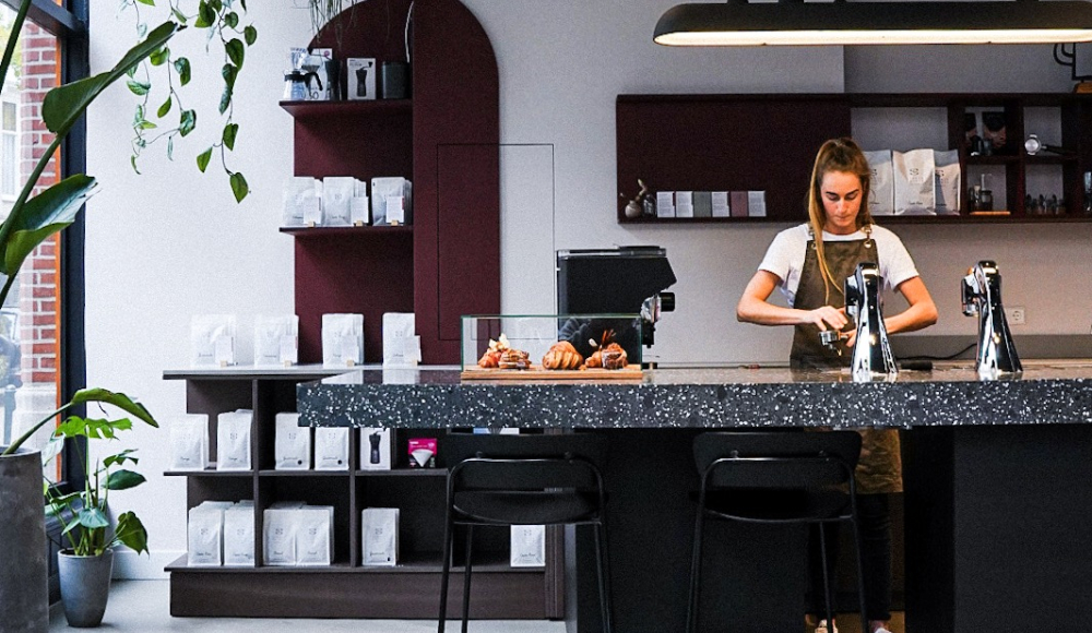 Barista met schort aan het werk in een moderne koffiebar.