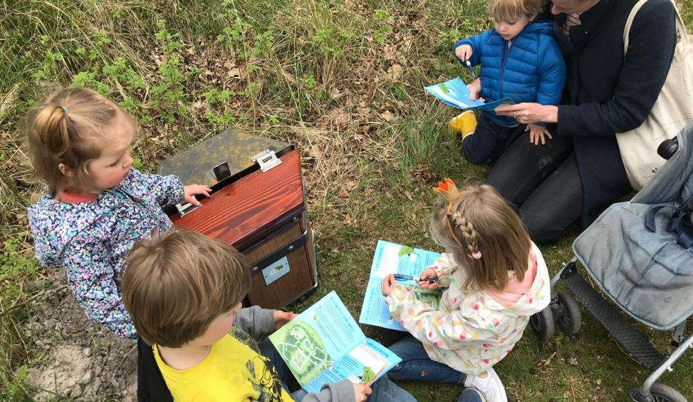 Kinderen bestuderen kaarten en spelen in de natuur.