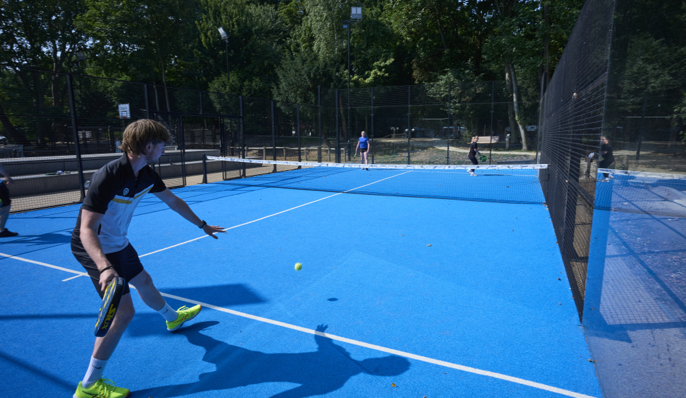 Ein Spieler schlägt einen Tennisball auf einem blauen Tennisplatz.