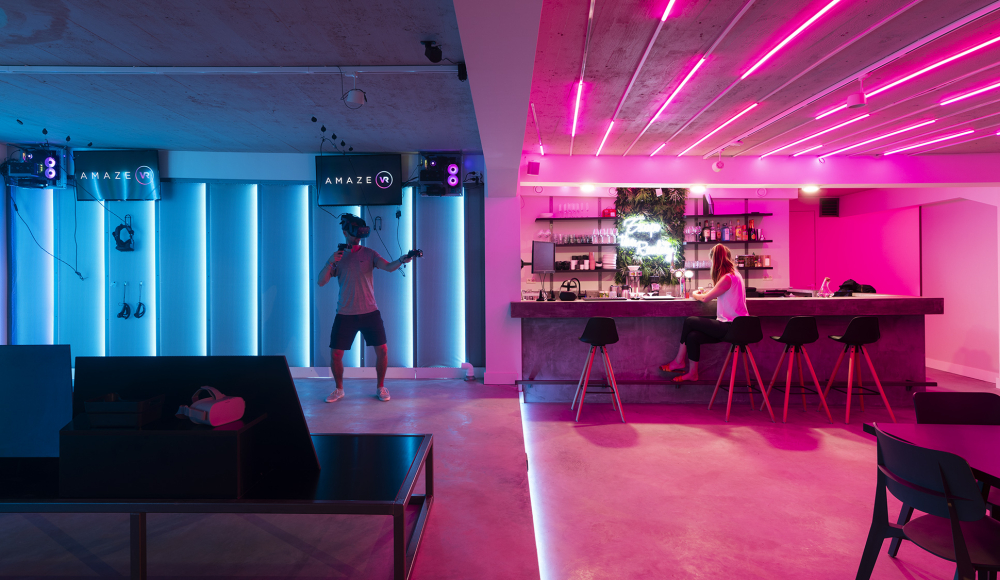 Amaze VR. Ein Mann spielt VR-Spiele, während eine Frau an der Bar sitzt.