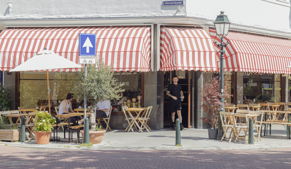 Zomerterrassen bij een café met rode strepen parasols.