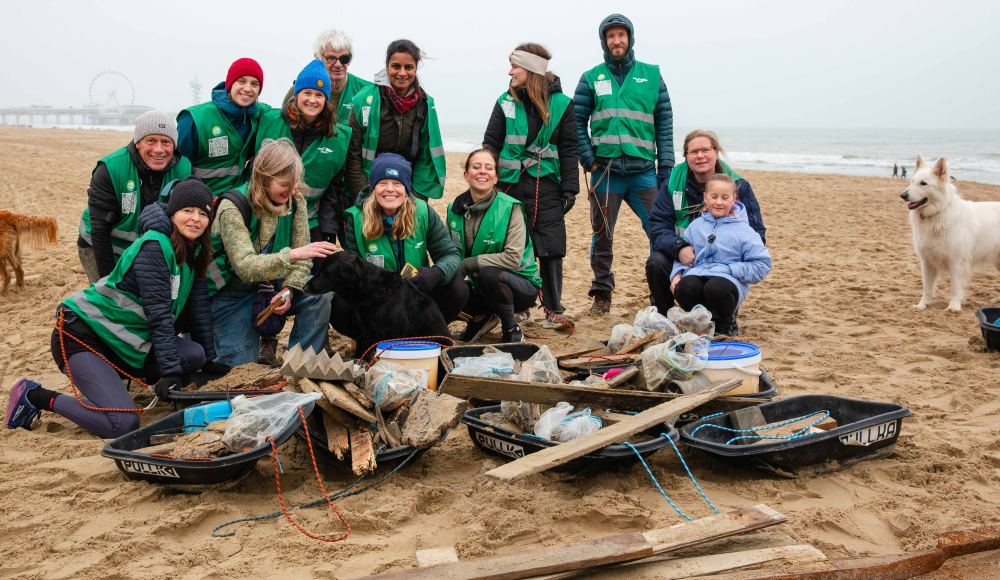 Vrijwilligers met zwarte hond reinigen het strand
