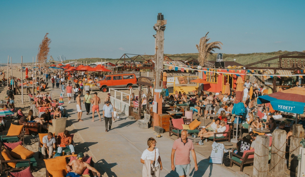 Drukke strandpromenade met mensen, stoelen en Zuid-Afrikaanse sfeer.
