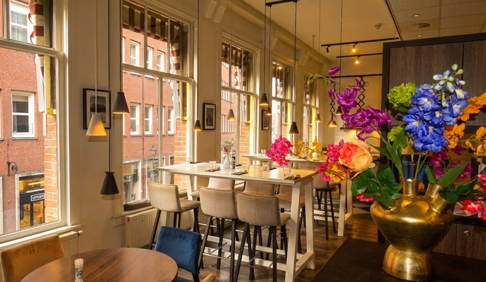 Bright café interior with large windows and colorful flowers