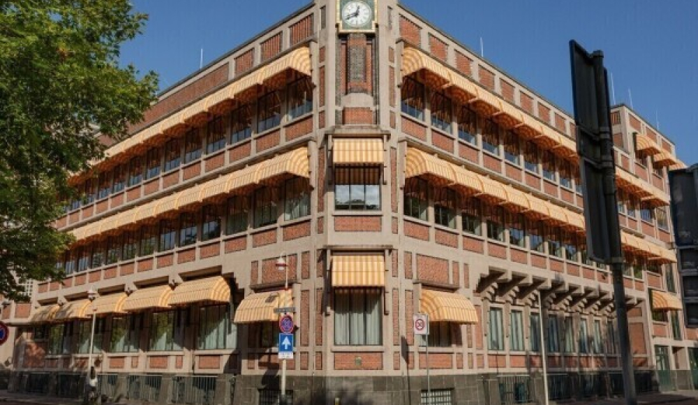Historisch hoekgebouw met oranje luifels en een klok.