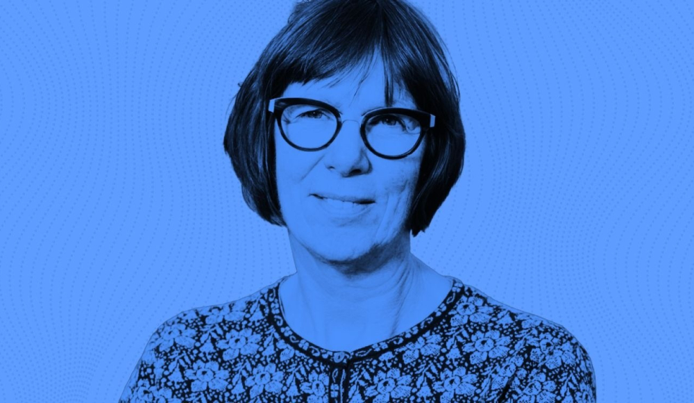 Vrouw met kort, bruin haar en bril, achtergrond in blauw