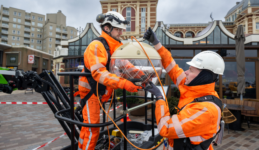 Twee mannen in oranje werkkleding aan de slag op boulevard Scheveningen.