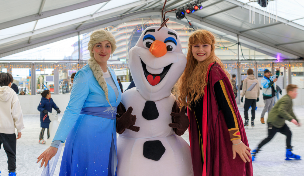 Anna, Elsa and Olaf from Frozen pose on an ice rink.