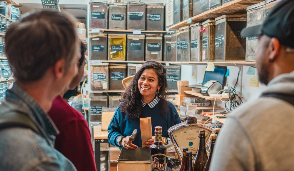 A smiling seller assists customers in a shop.