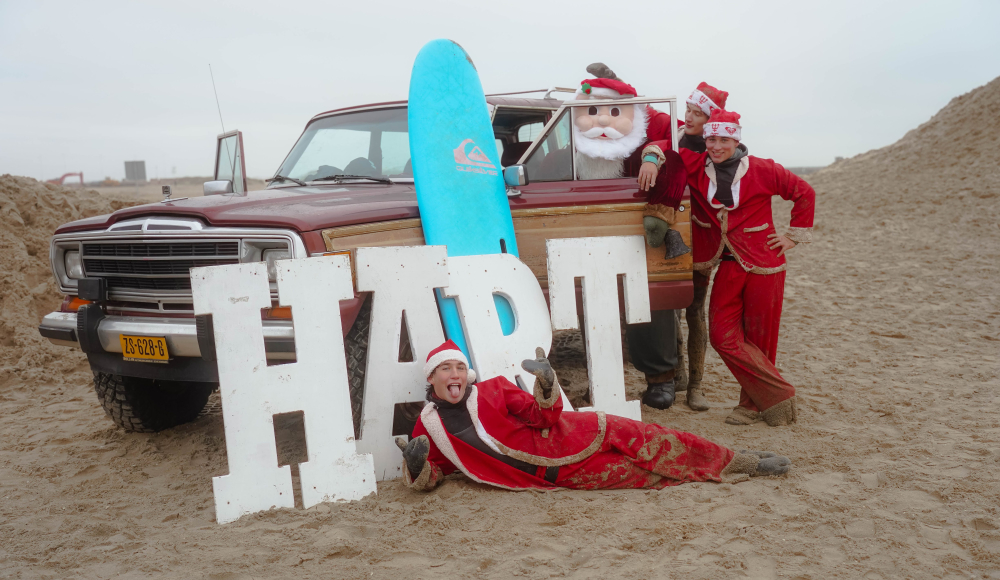Groep mensen in kerstkostuums met een surfplank