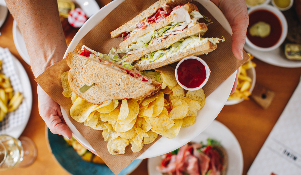 Een topshot van een clubsandwich in een bakje met chips