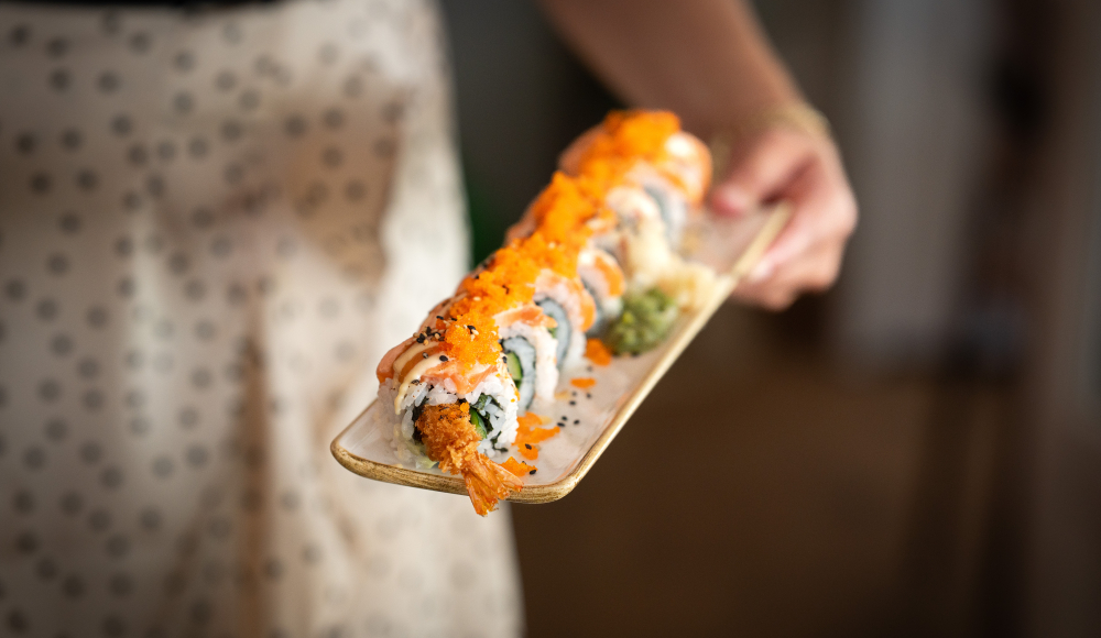 Eine Person hält einen Teller mit verschiedenen Sushi-Rollen.
