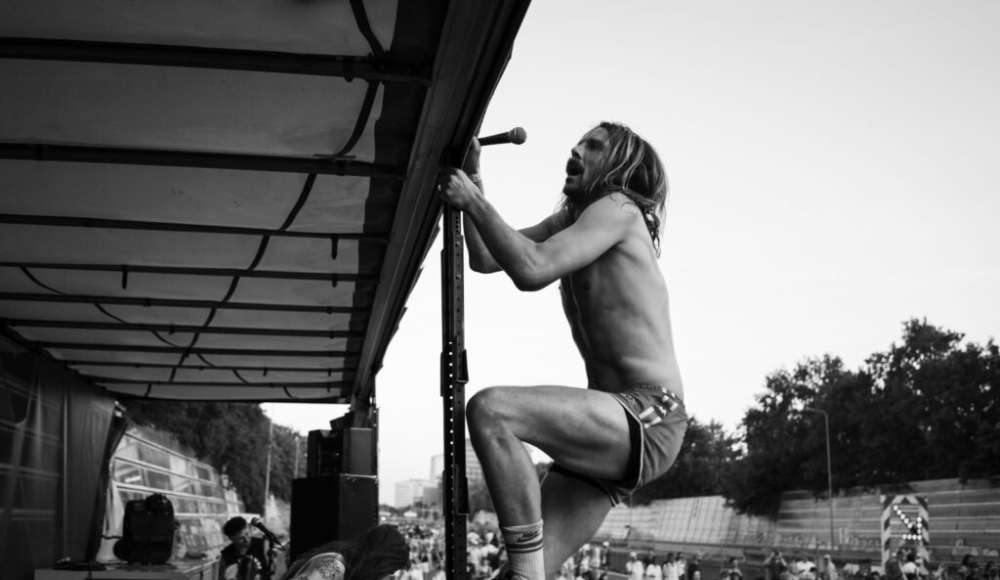 Een zanger klimt op een paal tijdens een optreden.