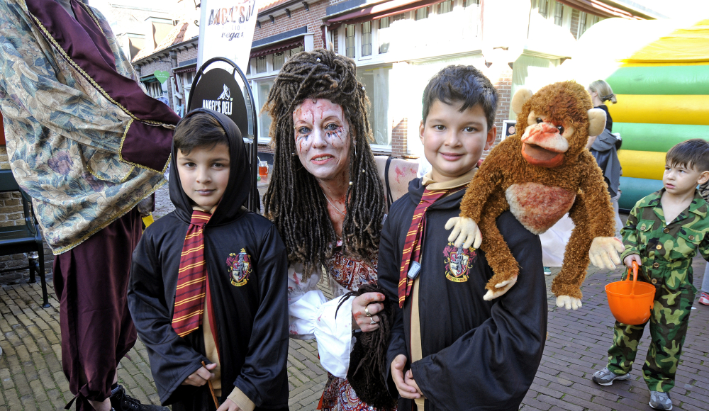Zwei Kinder in Harry-Potter-Kostümen mit einer Frau und einem Affen-Stofftier. Zwei Kinder in Harry-Potter-Kostümen mit einer Frau und einem Affen-Stofftier.