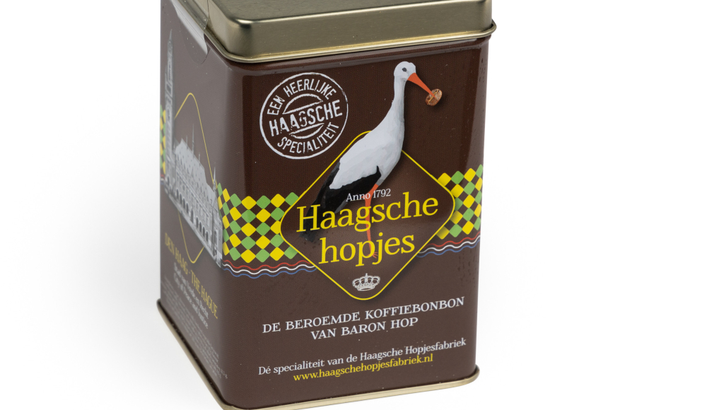 Een bruin blikje met de afbeelding van de ooievaar vol Haagsche Hopjes 