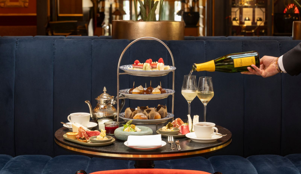 Een elegante tafel met high tea, inclusief thee, gebak en champagne.