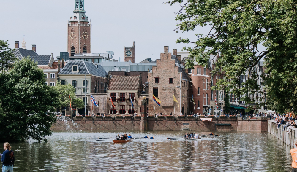 People rowing on the water with the Binnenhof in the background