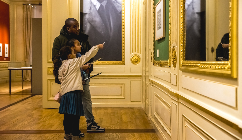 A man and two children are looking at art in a museum.