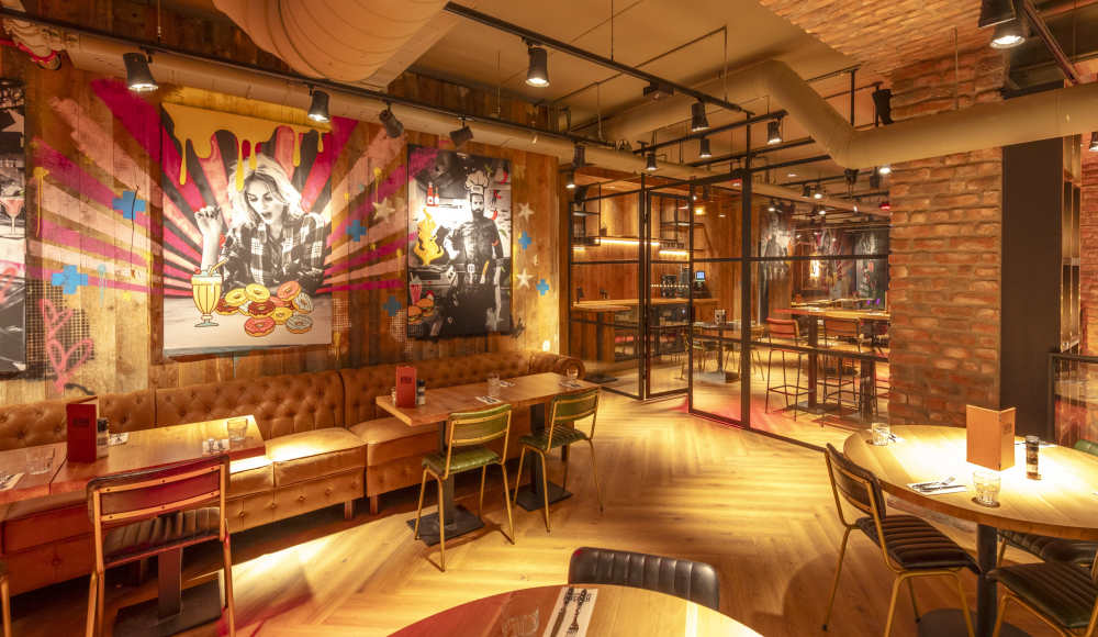 Modernes Restaurant mit Kunst an den Wänden und Holzmöbeln.