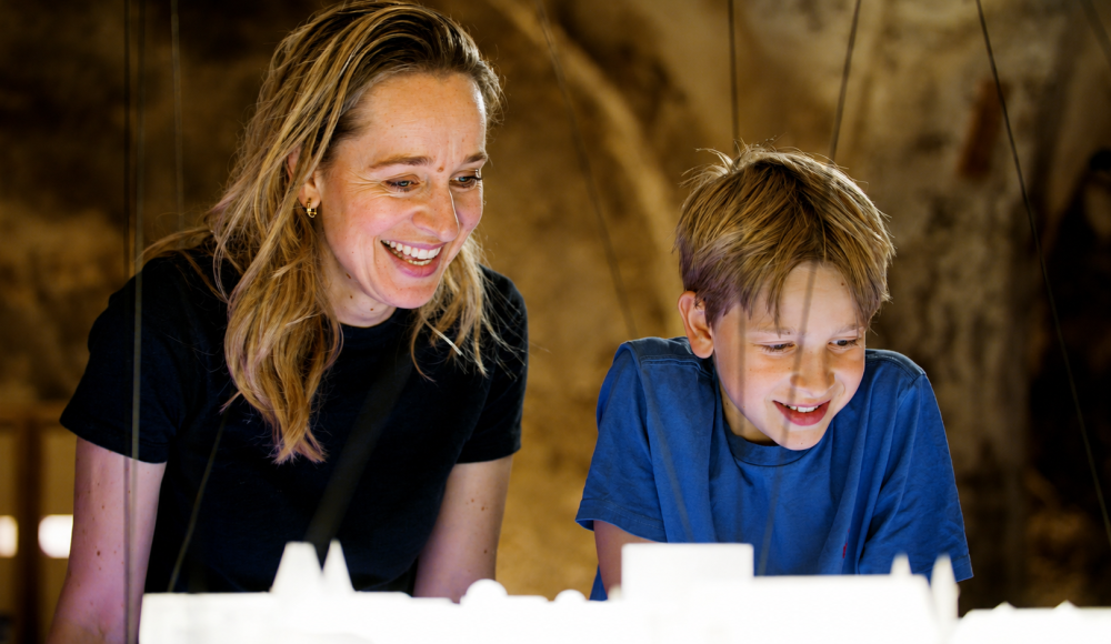 A woman and a boy are happily looking at a model.