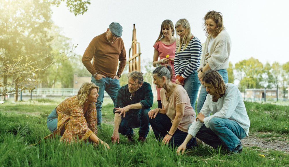Iederal. Eine Gruppe von Menschen schaut auf den Boden in einem Park.