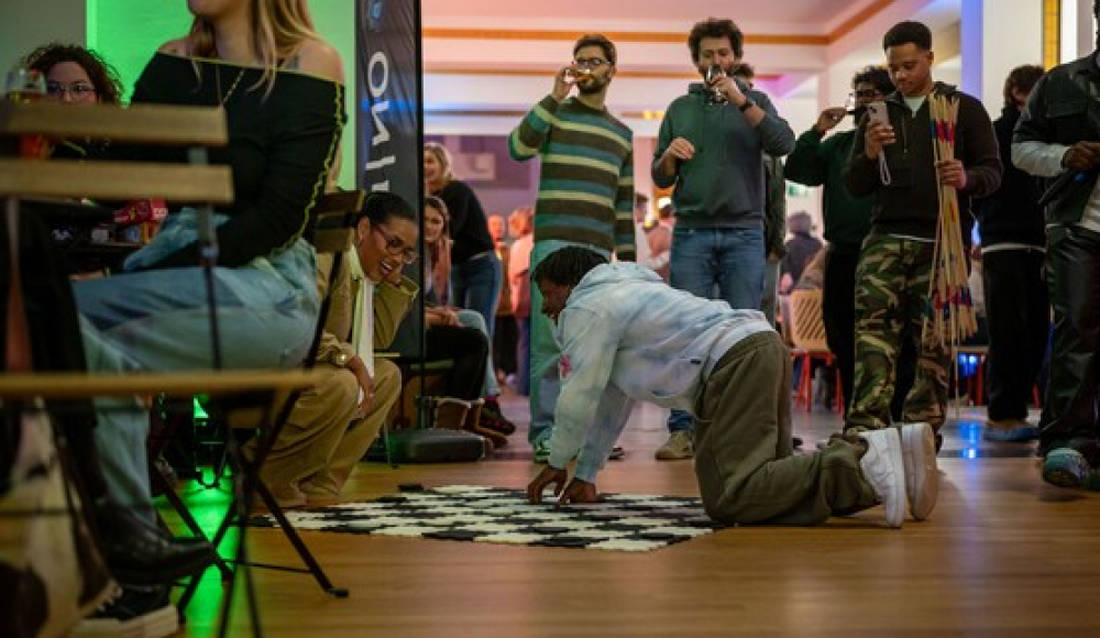 Mensen in een zaal tijdens een evenement, iemand op handen en knieën.