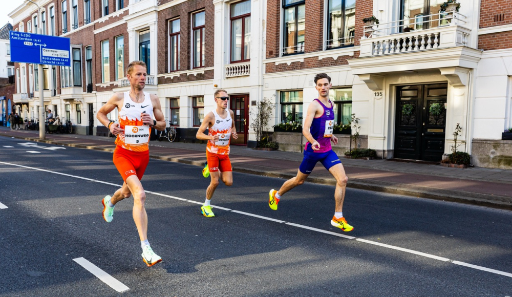 Drie hardlopers rennen op een straat in Den Haag.