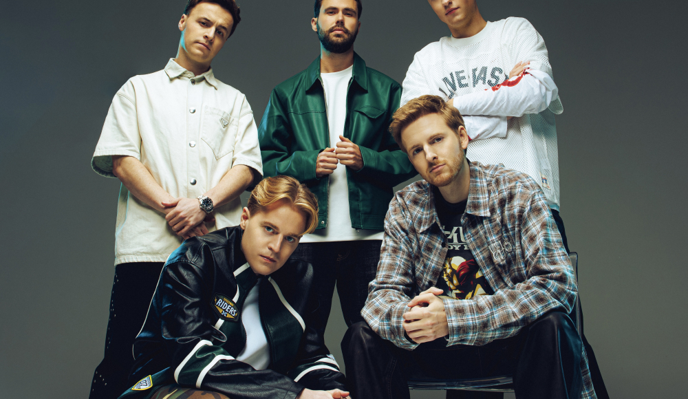 Fünf junge Männer posieren in lässiger Kleidung mit verschiedenen Stilen.